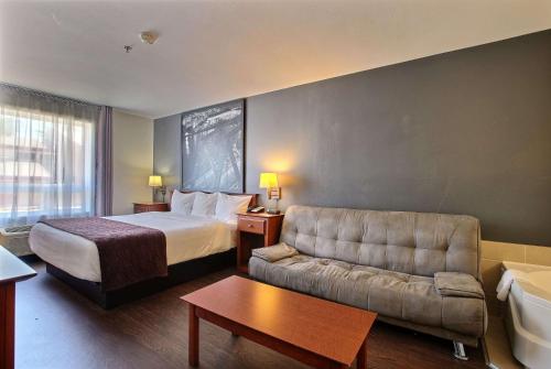 a hotel room with a bed and a couch at Super 8 by Wyndham Trois-Rivieres in Trois-Rivières