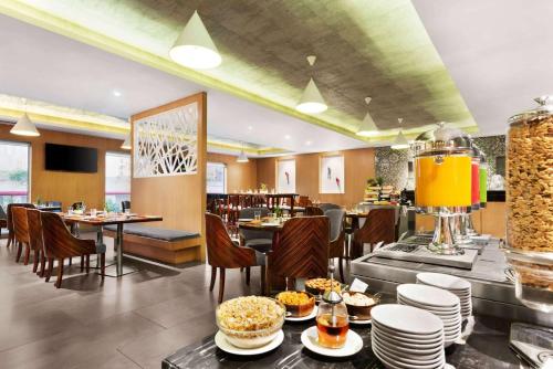 a restaurant with tables and chairs with food on them at Howard Johnson by Wyndham, Kolkata Airport in Kolkata