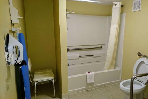 a bathroom with a shower and a toilet and a chair at Travelodge by Wyndham Knoxville East in Knoxville