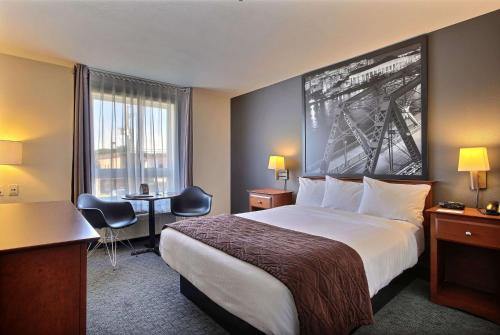 a hotel room with a large bed and a desk at Super 8 by Wyndham Trois-Rivieres in Trois-Rivières