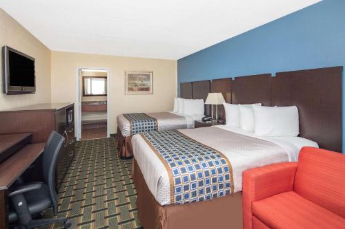 a hotel room with two beds and a chair at Travelodge by Wyndham Savannah Area/Richmond Hill in Richmond Hill