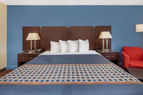a hotel room with a bed and a red chair at Travelodge by Wyndham Savannah Area/Richmond Hill in Richmond Hill