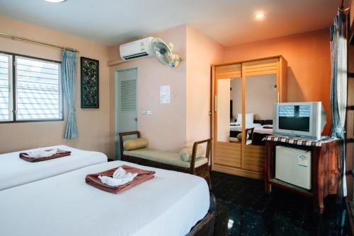a hotel room with two beds and a television at Noble Night Guesthouse in Kanchanaburi City
