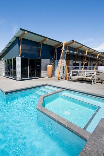 a large swimming pool in front of a building at Beach House Motel in Papamoa