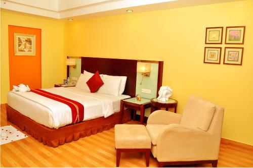 a hotel room with a bed and a chair at Gokulam Park Sabari-Siruseri SIPCOT in Chennai