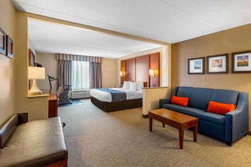 a hotel room with a bed and a blue couch at Comfort Suites Manassas Battlefield Park in Manassas