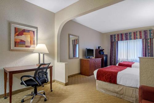 a hotel room with a bed and a desk with a chair at Clarion Suites Duluth I-85 in Duluth