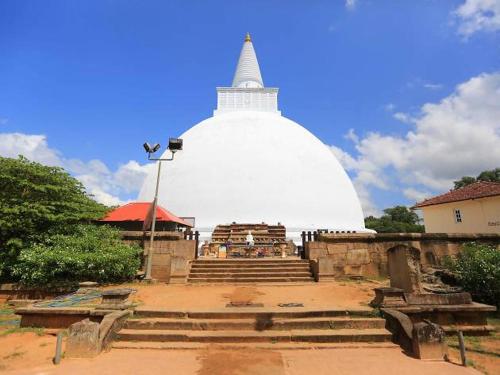 a large white building with stairs and a large white building at Olivia HomeStay in Anuradhapura