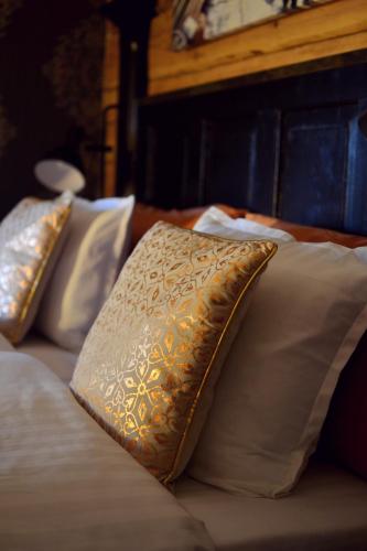 a bed with white pillows and a gold and white pillow at Putiikkihotelli Kemi 1932 in Kemi