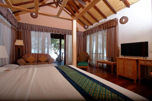 a hotel room with a bed, table, chairs and a television at Sutera @ Mantanani Island Resort & Spa in Mantanani Island