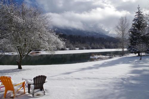 two chairs sitting in the snow next to a lake at Eau Vive in Lescheraines