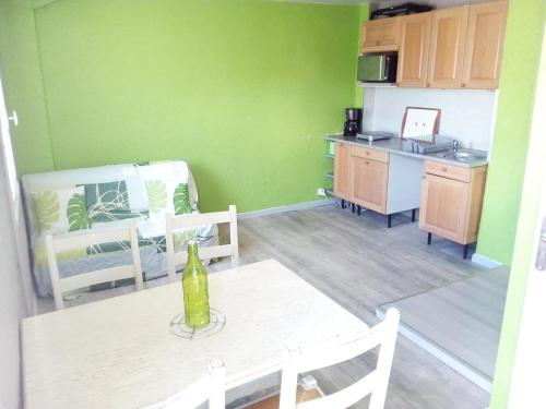 ヴァルラ・プラージュにあるcoquet appartement valras plageの緑の壁のキッチン(ボトル1本付きのテーブル付)