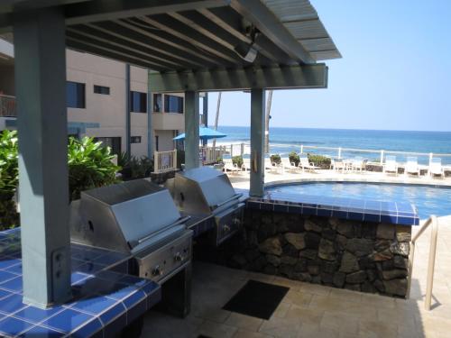 a patio with a grill and a swimming pool at Kona Reef Resort by Latour Group in Kailua-Kona