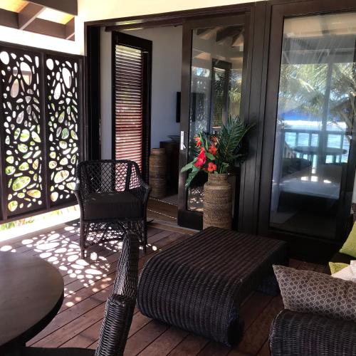 a porch with a ottoman and chairs on a patio at Serenity Villas Rarotonga in Rarotonga