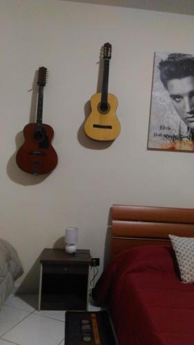 a bedroom with two acoustic guitars hanging on the wall at Sa Sindria in Cagliari