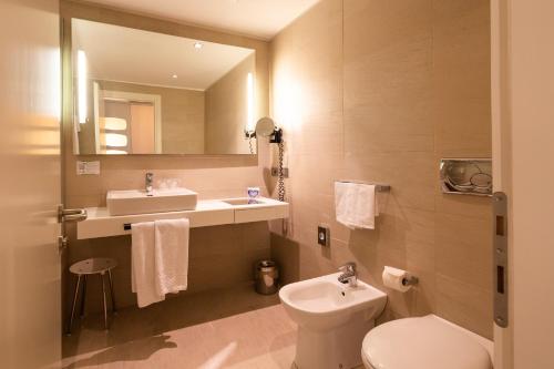 a bathroom with a toilet and a sink and a mirror at Best Western Plus Tower Hotel Bologna in Bologna
