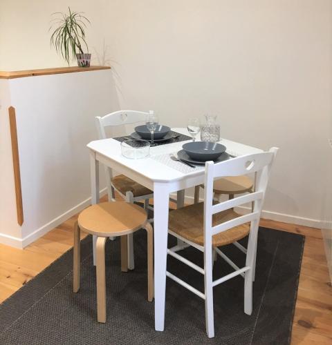 a white table and chairs with bowls and plates on it at Le T2 moderne des Palmiers au coeur de Moissac in Moissac