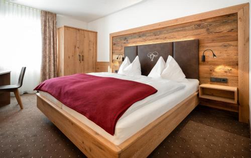 a bedroom with a large bed with a red blanket at Der Tröpolacherhof Hotel & Restaurant in Tröpolach