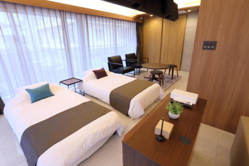 ein Hotelzimmer mit 2 Betten und einem Tisch in der Unterkunft Tabinoteitaku Okinawa Naha in Naha