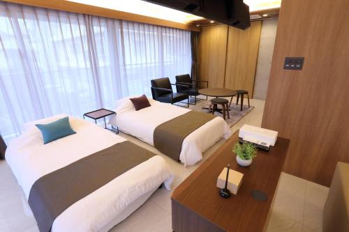 una habitación de hotel con dos camas y una mesa en Tabinoteitaku Okinawa Naha, en Naha