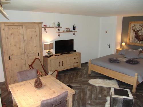 - une chambre avec un lit, une table et une télévision dans l'établissement Apartments Haus Quelle, à Loèche-les-Bains