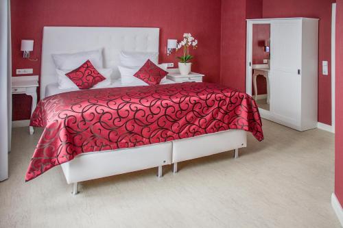 a red bedroom with a white bed with a red bedspread at Haus Hotel & Pension Villa Laluna in Blankenburg