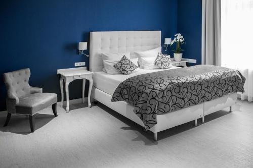 a blue bedroom with a bed and a chair at Haus Hotel & Pension Villa Laluna in Blankenburg