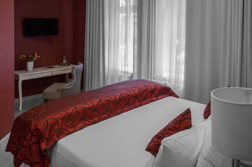 a bedroom with a bed with a red blanket on it at Haus Hotel & Pension Villa Laluna in Blankenburg