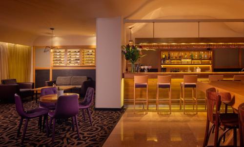 a restaurant with purple chairs and a bar at Prima Park Hotel Jerusalem in Jerusalem