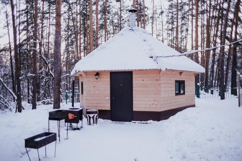 un pequeño edificio con techo cubierto de nieve en la nieve en Park Hotel Lesnye Dali, en Barnaul
