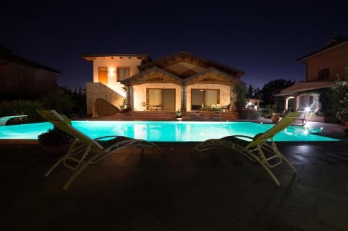 a pool with two chairs and a house at night at B&B A CASA DI ZIA LUISA in Venticano
