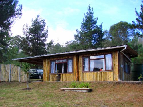 a small wooden house with a car in a yard at Hindthausen in Knysna