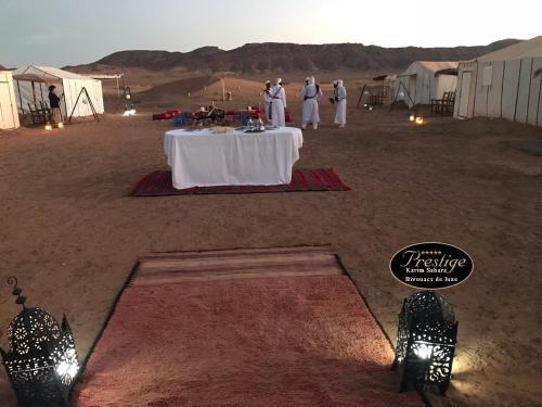 a table in the middle of a desert with tents at Karim Sahara Prestige in Zagora