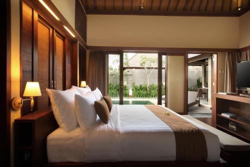 a bedroom with a large bed and a television at Nyuh Bali Villas in Seminyak