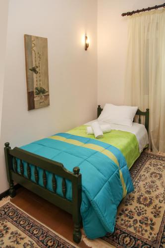 a bedroom with a bed with a blue and green blanket at The Villa of the Winds in Néa Kíos