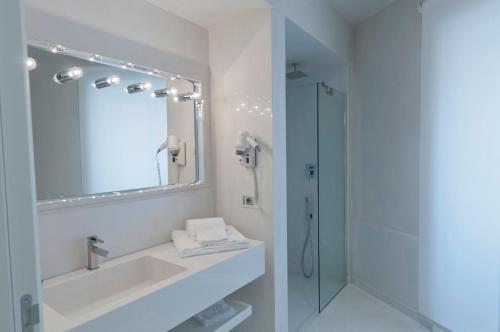 La salle de bains blanche est pourvue d'un lavabo et d'une douche. dans l'établissement Palazzo Favacchio - Patanè, à Scicli