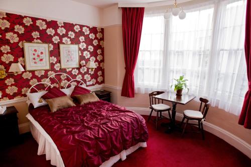 Dormitorio rojo con cama y mesa en The Market Inn, en Brighton & Hove