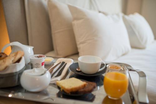 a tray with breakfast foods and drinks on a bed at Fontevraud L'Ermitage in Fontevraud-l'Abbaye