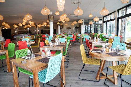un restaurant avec des tables en bois et des chaises colorées dans l'établissement Les Hauts de Beauval, à Saint-Aignan