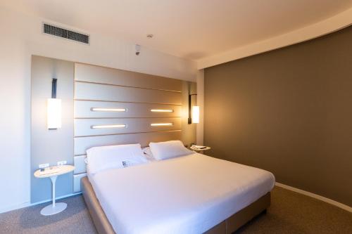 a bedroom with a large bed with white sheets at Best Western Plus Tower Hotel Bologna in Bologna