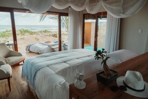 a bedroom with a bed and a view of the beach at Eclectic Beach Retreat in Cabo Nhamua