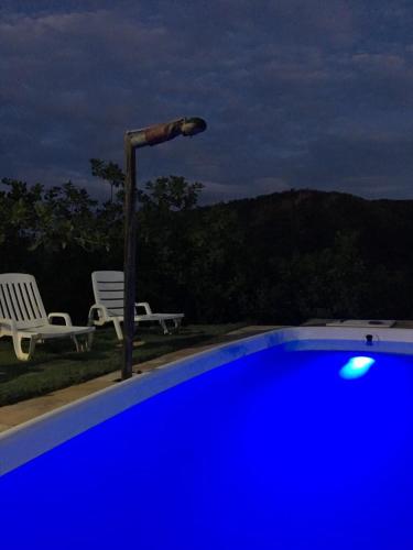 a blue swimming pool with two chairs and a street light at Pousada Trilha do Velho Chico in Piranhas