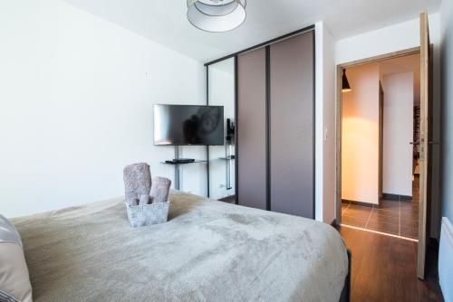a bedroom with a bed with a chair and a tv at T4 8 personnes de grand standing classé 4 étoiles en plein centre de Saint Lary Soulan in Saint-Lary-Soulan