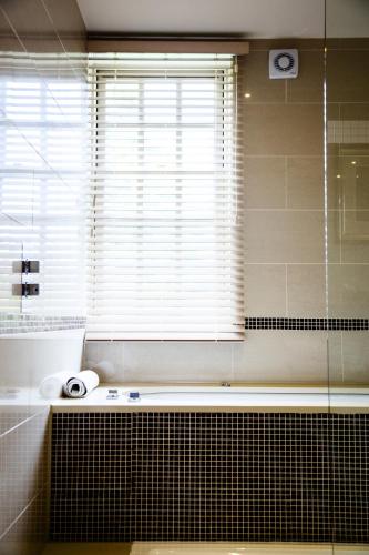 a bathroom with a window and a tub and a sink at Brockencote Hall in Kidderminster