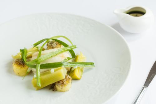 a white plate with pasta and green vegetables on it at Brockencote Hall in Kidderminster