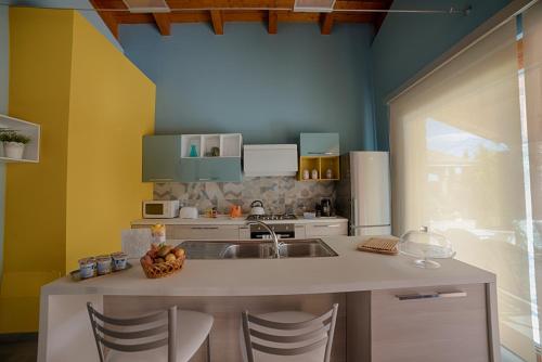 a kitchen with a sink and a counter with chairs at B&B A CASA DI ZIA LUISA in Venticano