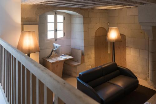 a living room with a couch and a desk with a computer at Fontevraud L'Hôtel in Fontevraud-l'Abbaye