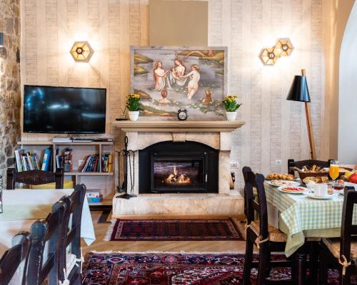 a living room with a fireplace and a dining table at Kaza Guesthouse in Dhimitsana