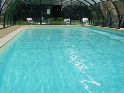 une grande piscine d'eau bleue avec 2 chaises dans l'établissement L'Edelweiss, à La Chapelle-en-Valgodemard