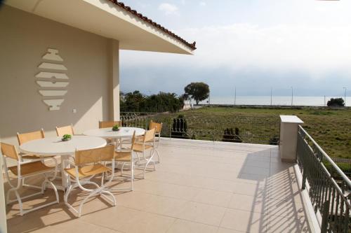 a patio with tables and chairs and a view of the ocean at The Villa of the Winds in Néa Kíos